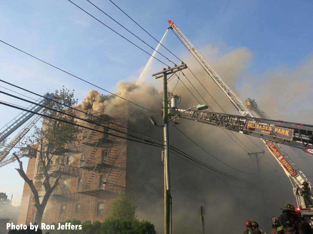 烟雾从Fort Lee的一座建筑的顶部喷出,来自不同消防部门的多个天线正在使用