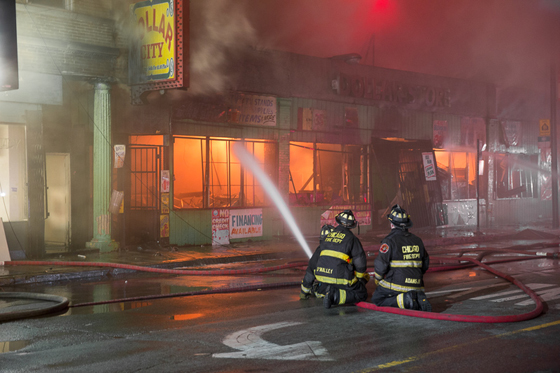 芝加哥的消防队员在一排商店的火场上训练一条长统袜。