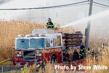 纽约消防局的消防队员们在一台设备上向斯塔顿岛的丛林大火喷水。
