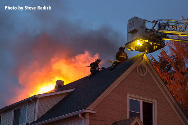 消防队员在芝加哥一座着火房屋的屋顶上。