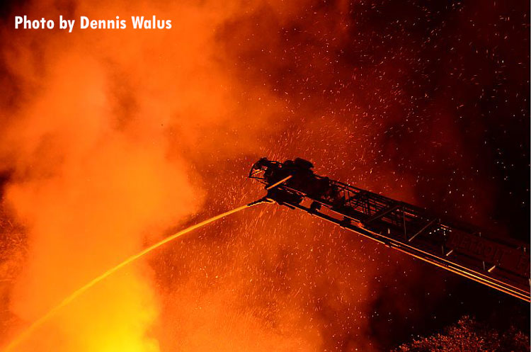 消防员在底特律的居住火灾时经营一股空中流。