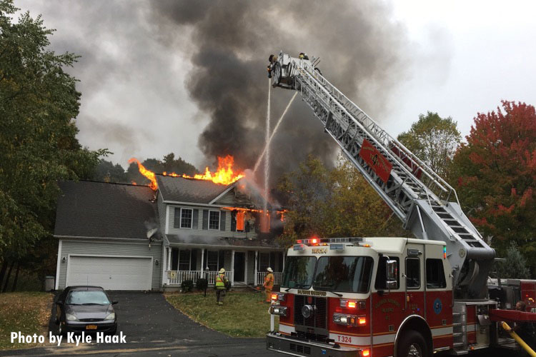 消防队员向着火的房屋外泼水。