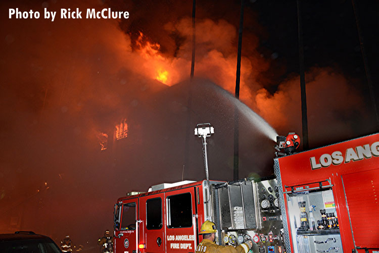 洛杉矶消防局的消防员正在往着火的公寓楼里浇水